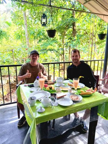 エッラにあるGreen Lanternの2人の男性が食べ物と飲み物を持ってテーブルに座っている