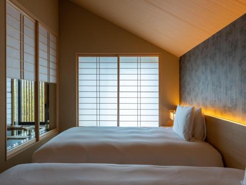 a bedroom with two beds and a large window at Fufu Kyoto in Kyoto