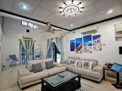 een woonkamer met 2 banken en een plafondventilator bij Yussy Homestay at Afamosa Villa in Kampong Alor Gajah