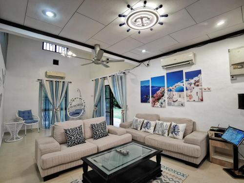 a living room with two couches and a ceiling fan at Yussy Homestay at Afamosa Villa in Kampong Alor Gajah