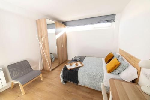 a bedroom with a bed and a chair and a mirror at Amplio piso de diseño . in Vigo