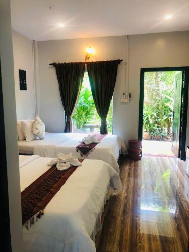 a hotel room with four beds and a large window at Moloppor Villa in Battambang