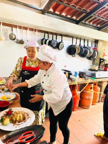 two women standing in a kitchen preparing food at Moloppor Villa in Battambang