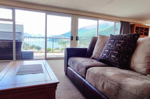 a living room with a couch and a glass table at Spacious Home with Awesome Lake Views in Queenstown