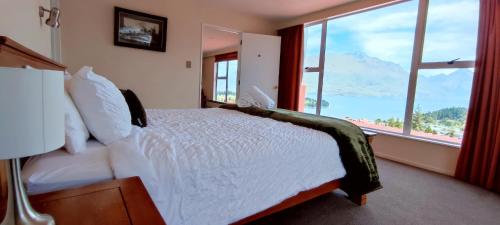 a bedroom with a bed and a large window at Spacious Home with Awesome Lake Views in Queenstown