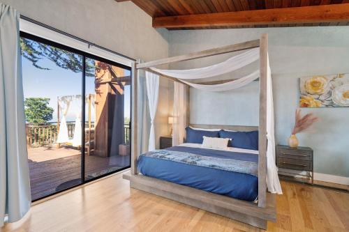 1 dormitorio con cama con dosel y balcón en @ Marbella Lane - 3BR Home w/sweeping ocean views!, en Pacífica