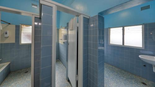 La salle de bains est pourvue de murs carrelés bleus et d'un lavabo. dans l'établissement Commercial Travellers House, à Gulgong