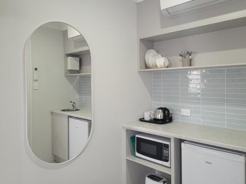 una pequeña cocina con lavabo y espejo en Araluen Motor Lodge, en Batemans Bay