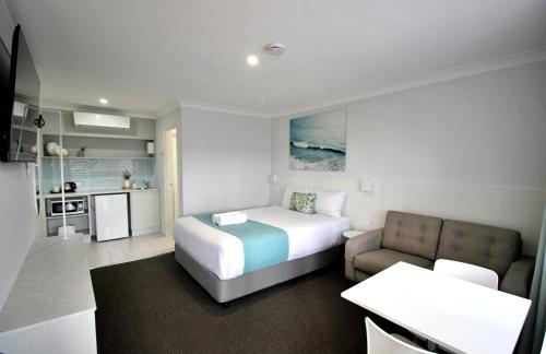 a hotel room with a bed and a kitchen at Araluen Motor Lodge in Batemans Bay