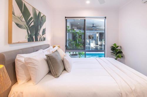 ein Schlafzimmer mit einem großen Bett mit weißen Kissen in der Unterkunft Pembroke House - Inner city luxury in Cairns
