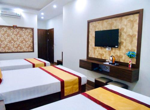 a hotel room with two beds and a flat screen tv at Tình Hiếu Hotel in Ha Long