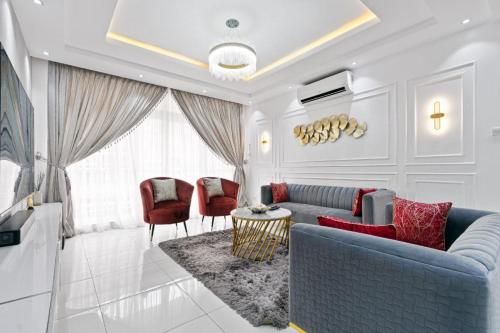 a living room with a blue couch and red chairs at Luxury 3 Bedroom Apartment In Lekki Phase1 in Lekki