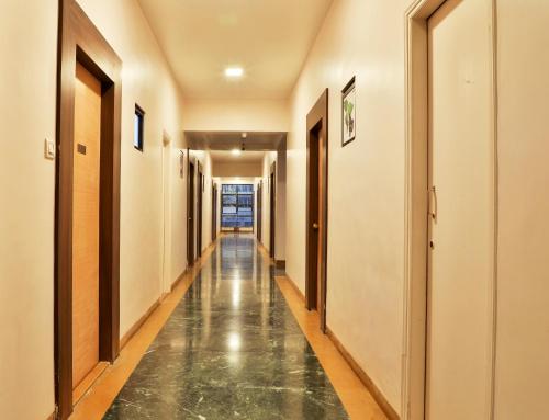 a corridor of a building with a reflective floor at Saish Hotel Shirdi in Shirdi