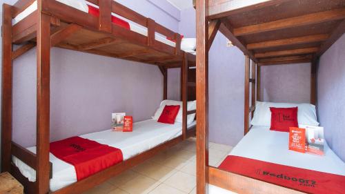 two bunk beds in a room with red and white sheets at RedDoorz @ Golden Travellers Inn Antique in Hamtic
