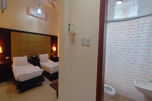 Habitación de hotel con 2 camas y lavamanos en Khorfakkan Hotel Apartments, en Khor Fakkan