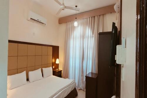 1 dormitorio con cama blanca y ventana en Khorfakkan Hotel Apartments, en Khor Fakkan