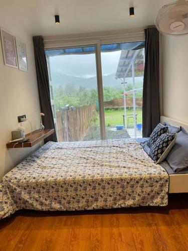 a bedroom with a bed and a large window at The Silver Lining - 2 bhk Villa facing the hills in Karjat