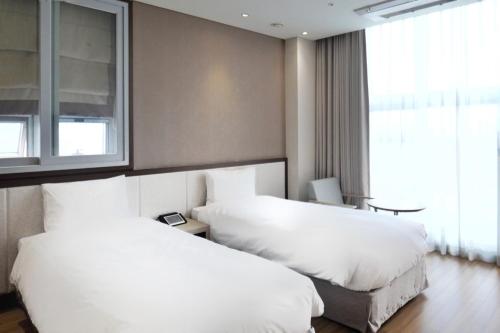 a hotel room with two white beds and a window at Rosana Hotel in Seoul