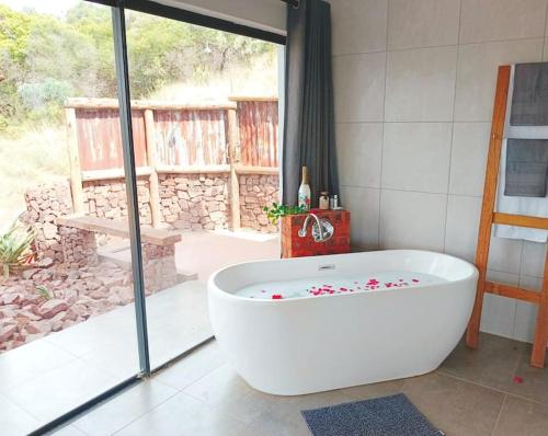 bañera blanca en una habitación con ventana en Rocky Road Mountain Lodge, en Pretoria