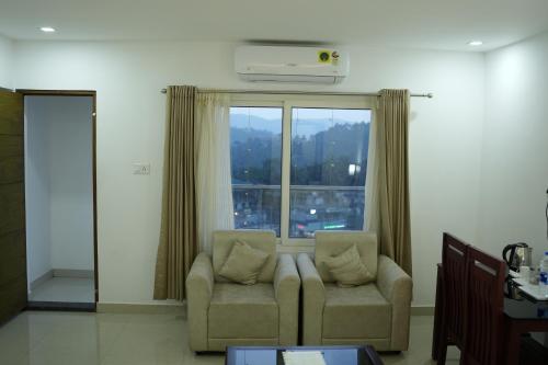 a living room with a couch and a large window at RJ ROSS RAMAPURAM in Munnar