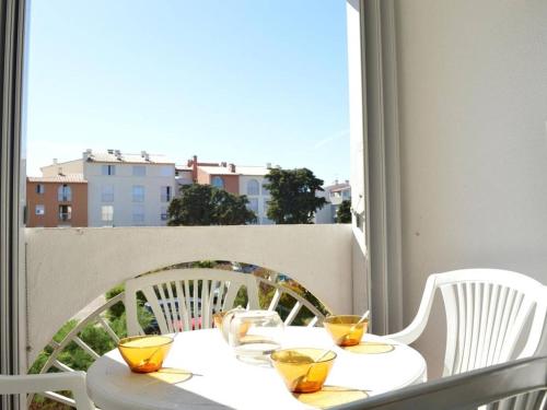 une table blanche avec des lunettes jaunes sur un balcon dans l'établissement Studio cosy à 1200m de la plage, à proximité commerces, port et golf, parking privé inclus - FR-1-249-13, au Cap d'Agde