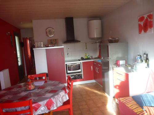 une cuisine avec des placards rouges et une table avec une nappe dans l'établissement Appartement 6 pers, terrasse, à 2 pas de plage et commerces, parking, option Internet - FR-1-387-153, à Marseillan