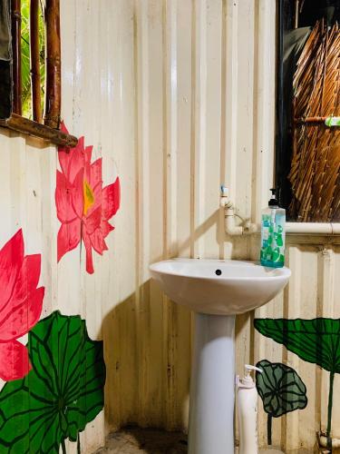 a bathroom with a white sink and flowers on the wall at Saigon Garden Homestay in Ho Chi Minh City