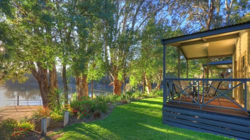 a house with a gazebo in the grass near a lake at Moama Riverside Holiday Park in Moama