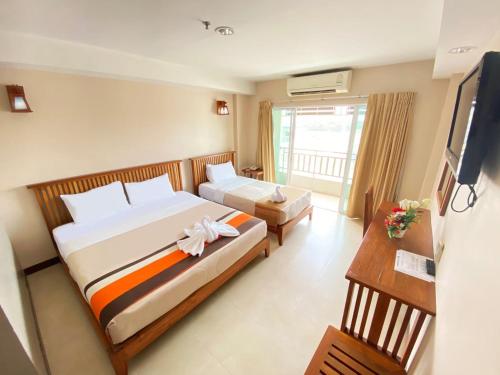 a hotel room with two beds and a television at Maihom Resort Hotel in Nakhon Sawan