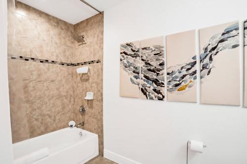 a bathroom with a sink and a shower with three paintings at Blue on Fox Run in Apollo Beach