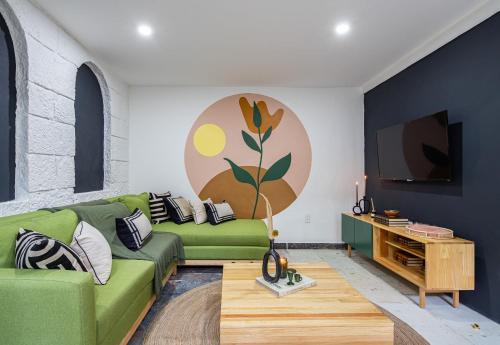 a living room with a green couch and a tv at Sleeps 9, Outdoor Space, PingPong Table, in Villa in Oaxaca City