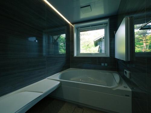 a bathroom with a bath tub and a window at MAOIQ in Naganuma