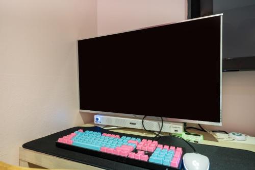 a computer keyboard and mouse on a desk with a monitor at Laria Hotel in Suwon