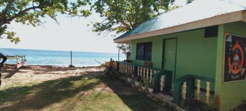 安達的住宿－1peace beach resort，一座绿色建筑,设有毗邻大海的门廊