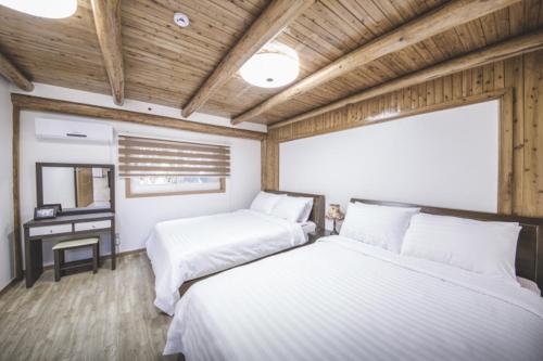 two beds in a room with wooden ceilings and a desk at Sunyang Village Dome Caravan in Jeju