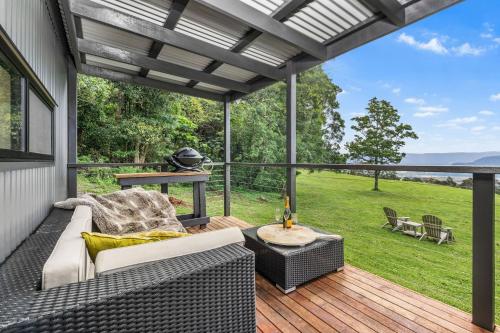 a patio with a couch and a table on a deck at Altitude Kangaroo Valley in Kangaroo Valley