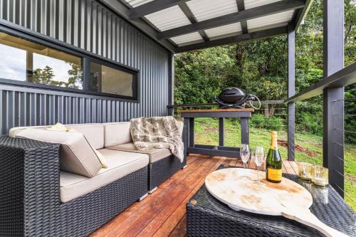 a patio with a couch and a table with wine glasses at Altitude Kangaroo Valley in Kangaroo Valley