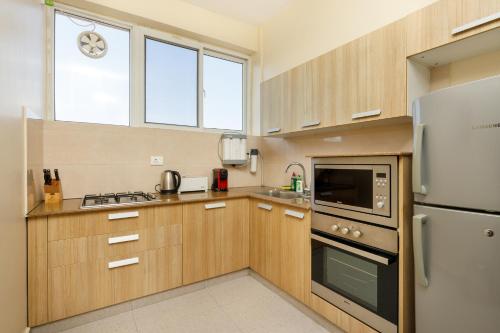 a kitchen with wooden cabinets and a refrigerator at Shaligram Hotel in Pātan
