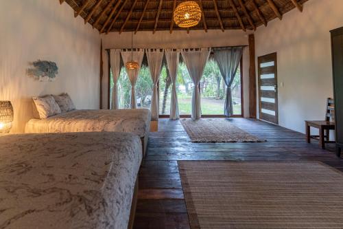 een slaapkamer met 2 bedden en een groot raam bij Xoot’ka’ana Villa Colibri in Bacalar