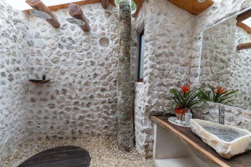 een badkamer met een wastafel en een stenen muur bij Xoot’ka’ana Villa Colibri in Bacalar
