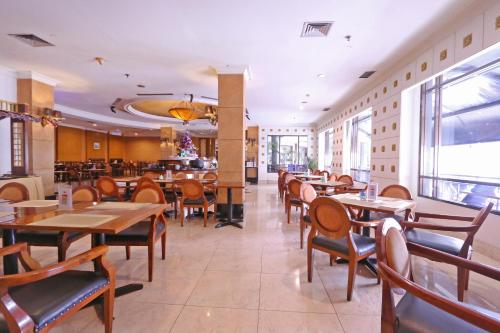 Hotel Kaisar في جاكرتا: مطعم بطاولات وكراسي خشبية وبار