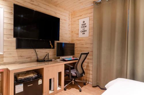a bedroom with a desk with a television and a chair at Laria Hotel in Suwon