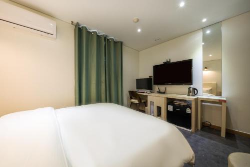 a hotel room with a bed and a flat screen tv at Laria Hotel in Suwon