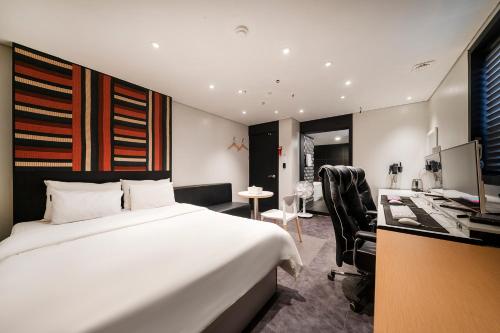 a bedroom with a large white bed and a desk at Laria Hotel in Suwon