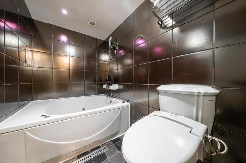 a bathroom with a white toilet and a bath tub at Laria Hotel in Suwon