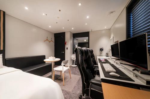 a bedroom with a bed and a desk with a computer at Laria Hotel in Suwon
