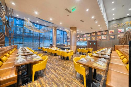 un restaurante con mesas de madera y sillas amarillas en Holiday Inn Kolkata Airport by IHG, en Calcuta