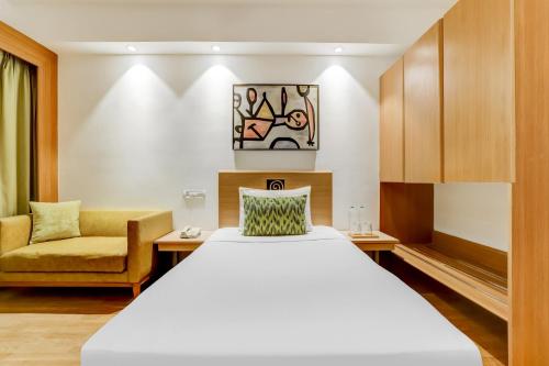 Pokój hotelowy z łóżkiem i krzesłem w obiekcie Lemon Tree Hotel, Ahmedabad w mieście Ahmadabad