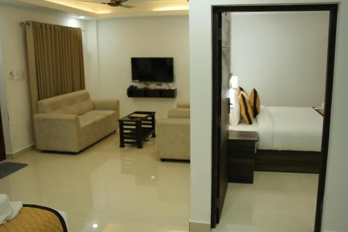 a hotel room with a bed and a couch and a television at RJ ROSS RAMAPURAM in Munnar