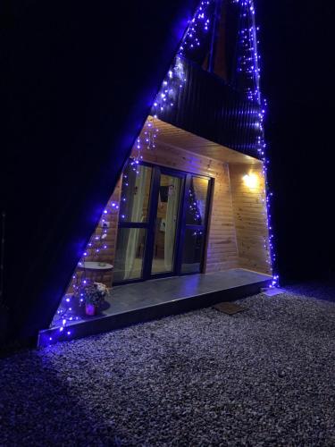 a small wooden house with christmas lights on it at Liniștea Muntilor Cartioasra in Cîrţişoara
